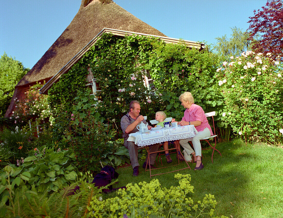 Grandparents & grandson in garden idyll, Hollaender Hof in Wagersrott Schleswig-Holstein, Germany Location aus der Fernsehserie Der Landarzt Wohnsitz des Kraeuterdoktors