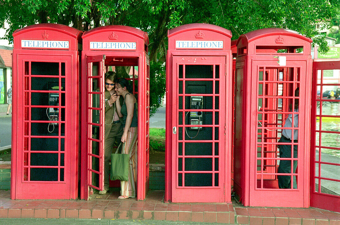 Young couple standing in telephone box, St. George´s, Grenada, Caribbean, America