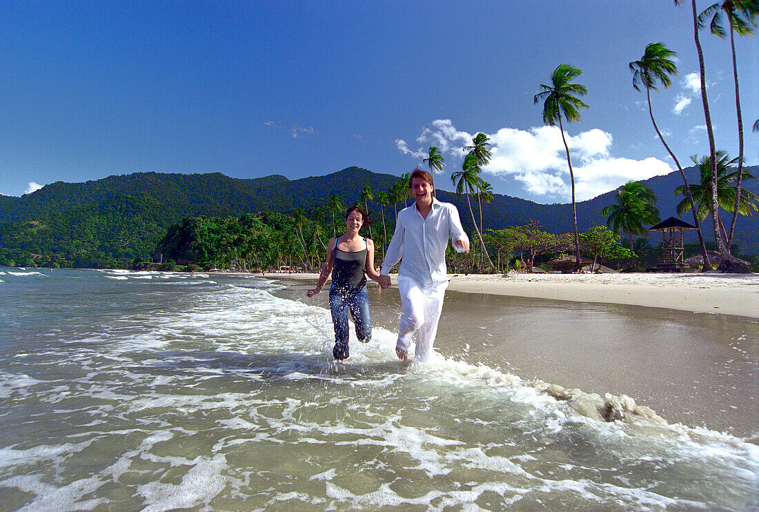 Young couple running at Maracas Bay, Trinidad, Caribbean