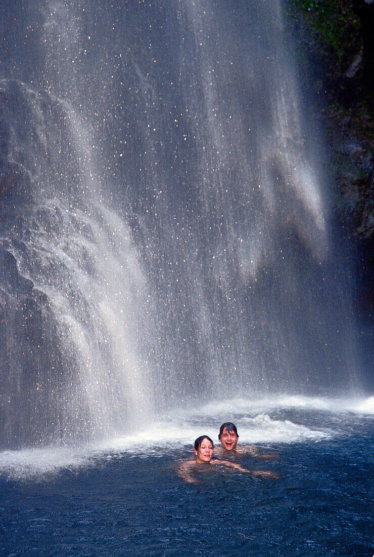 Couple swimming under waterfall, Falls of Balleine, St. Vincent, Caribbean