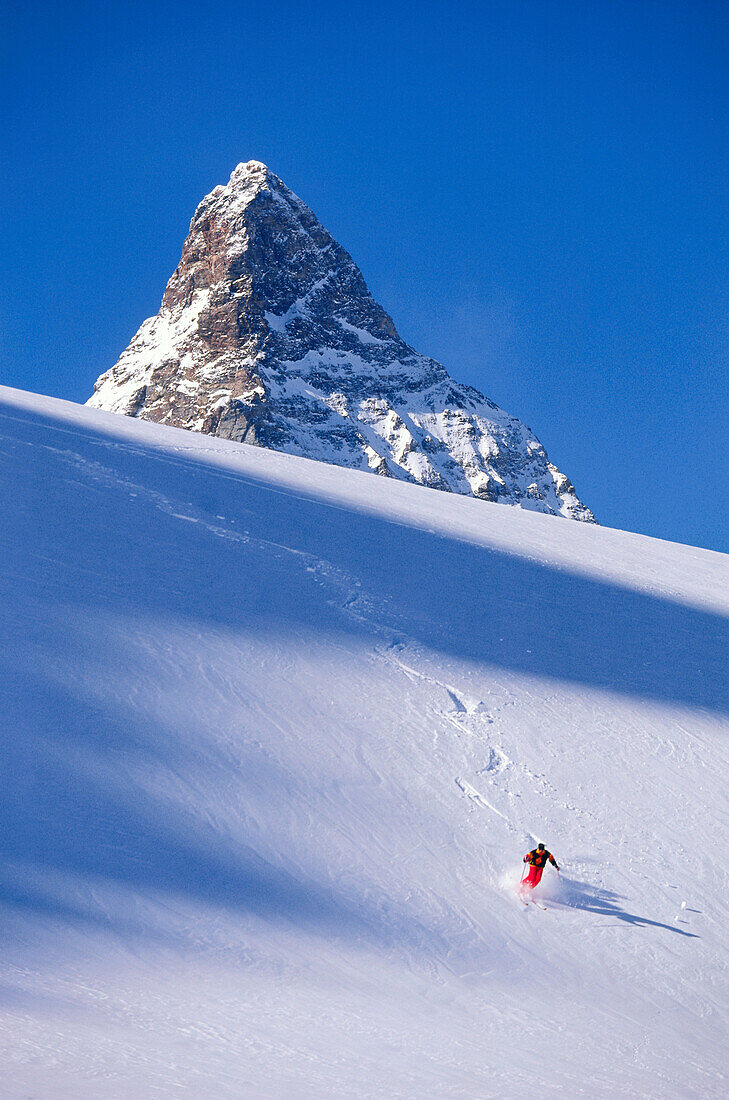 Young man skiing in deep powder snow in front of Matterhorn, Grisons, Switzerland