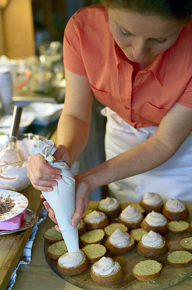 A woman filling muffins at a bakery