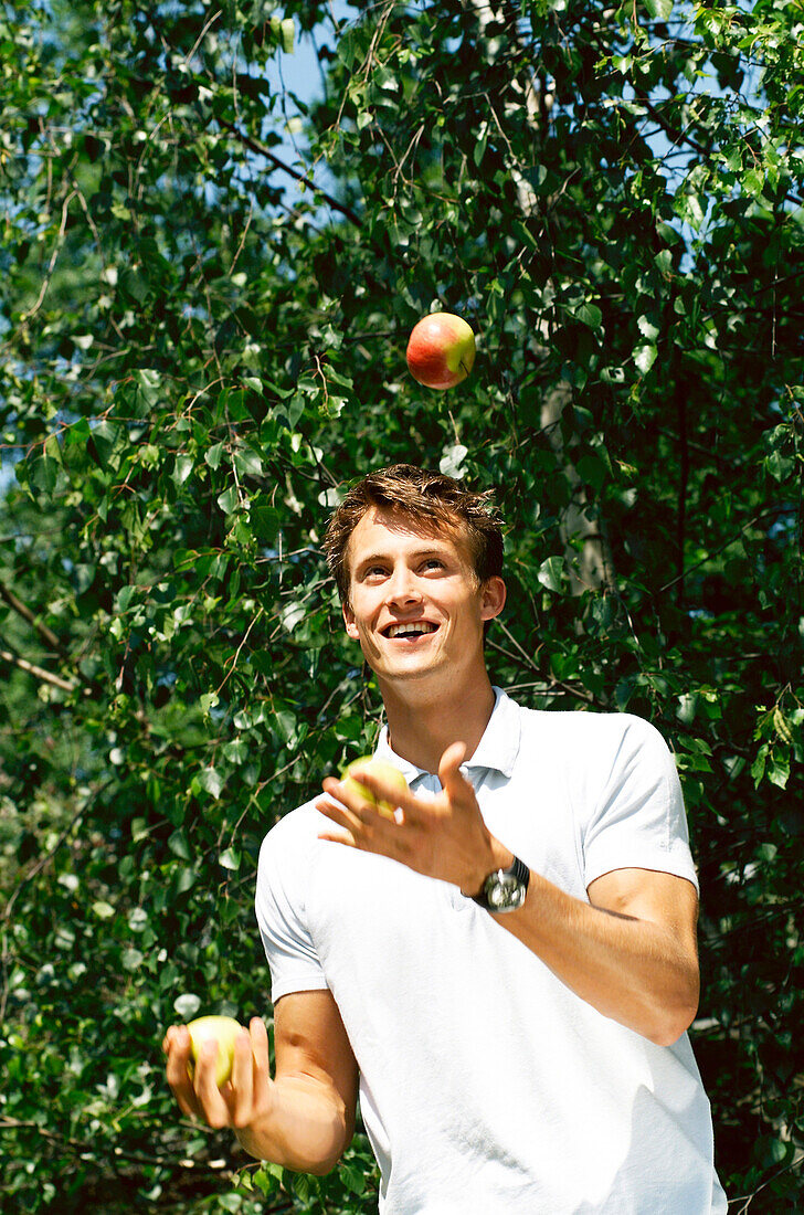 Mann jongliert mit Äpfeln