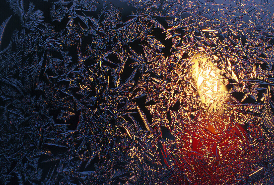 Kerze hinter mit Eiskristallen bedecktem Fenster