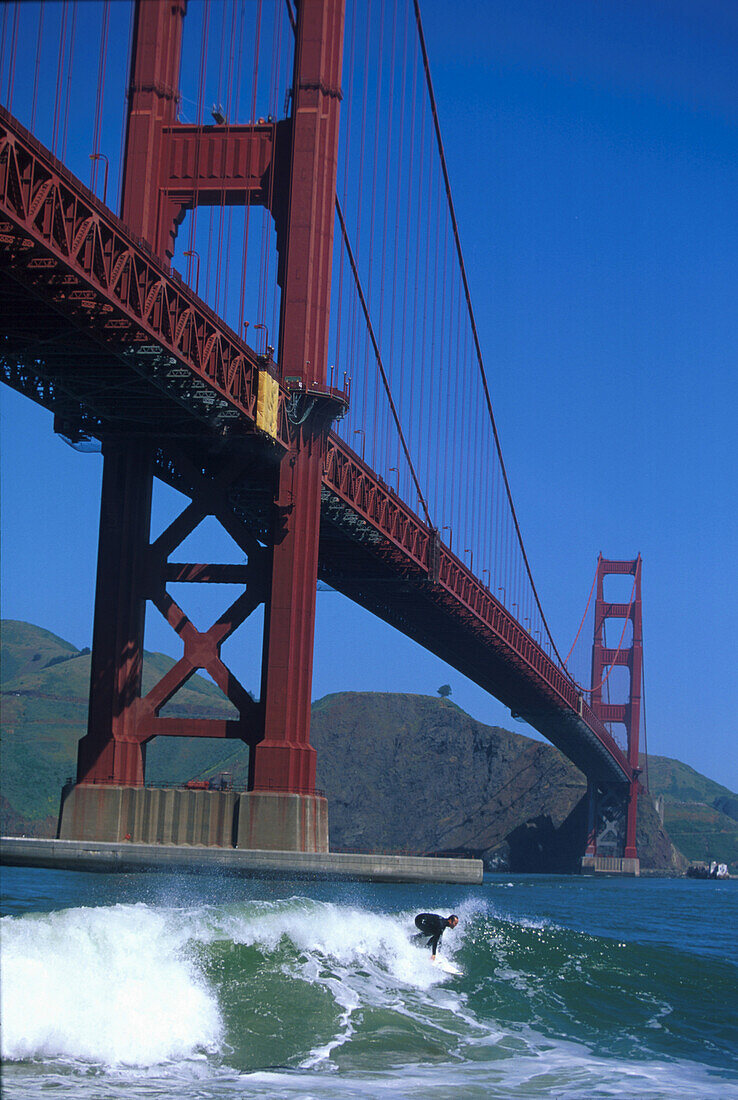 Surfer in front of Golden Gate Bridge under blue sky, San Francisco, California, USA, America