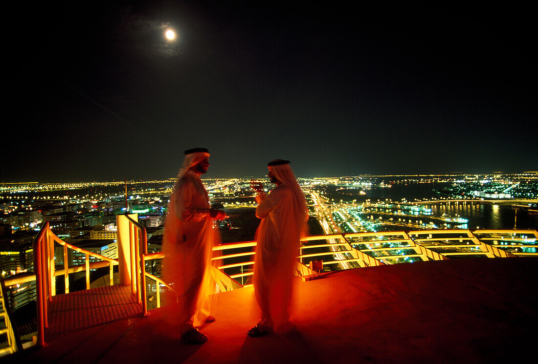 Scheichs stehen nachts auf einer Dachterrasse, Bur Deira, Dubai, Vereinigte Arabische Emirate