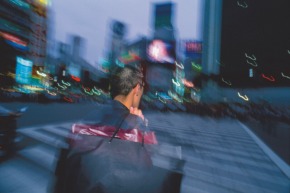 Man with carrier bag in front of high rise buildings, Tokyo, Japan, Asia