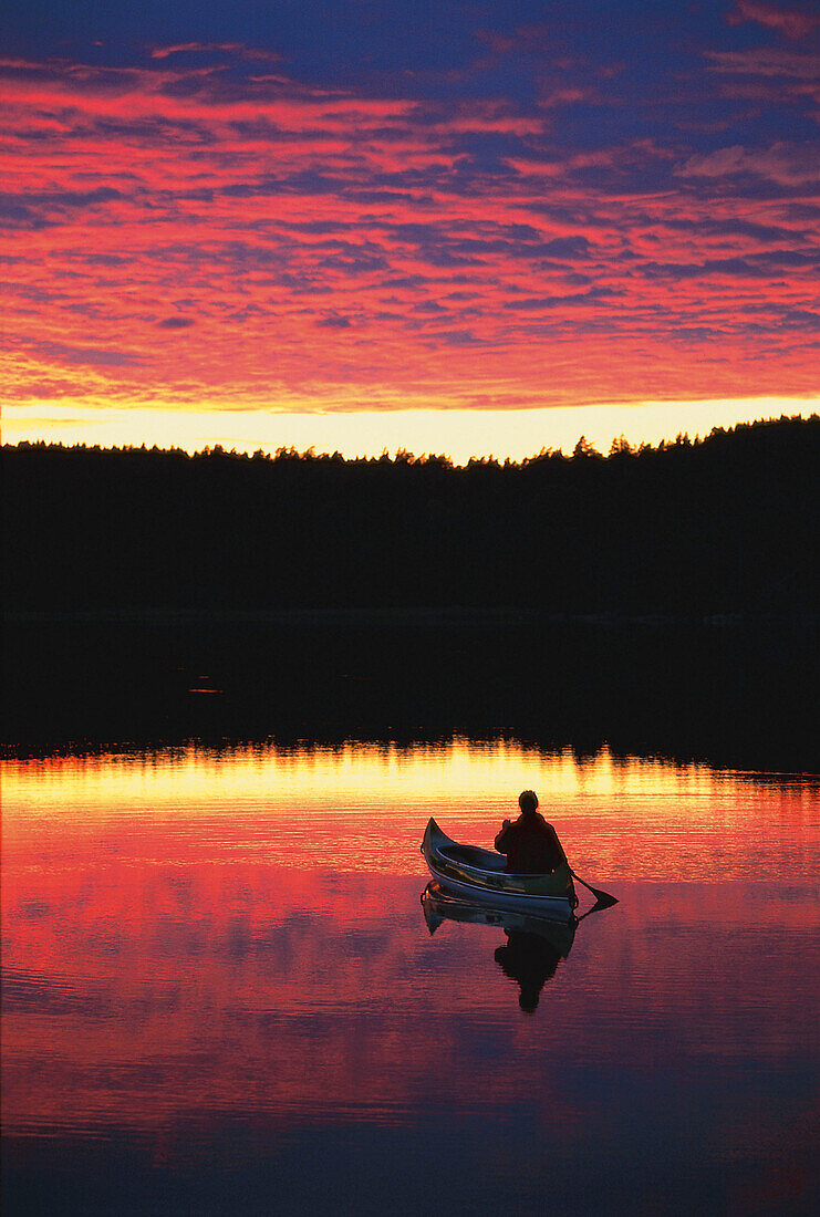 Canoe on lake at sunset, Vaestergoetland, Schweden