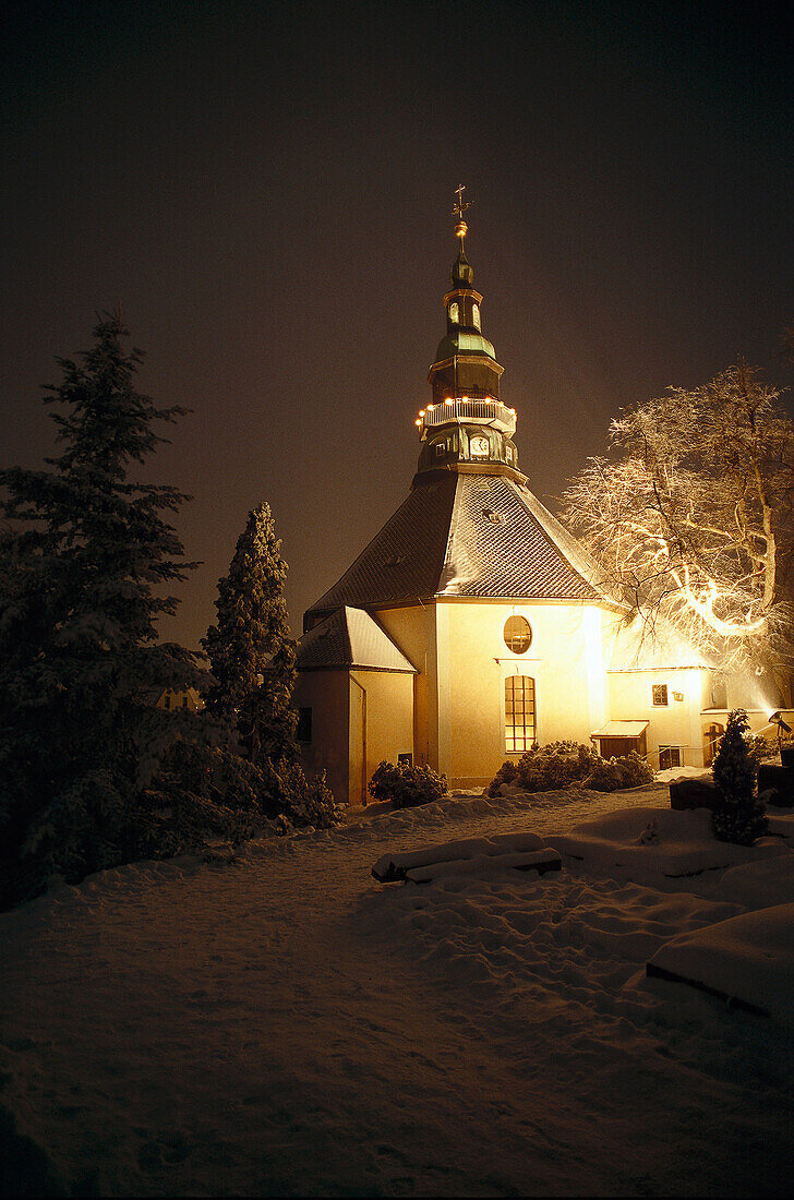 Illuminated chapel in the Erz Mountains at night in winter, Saxony, Germany