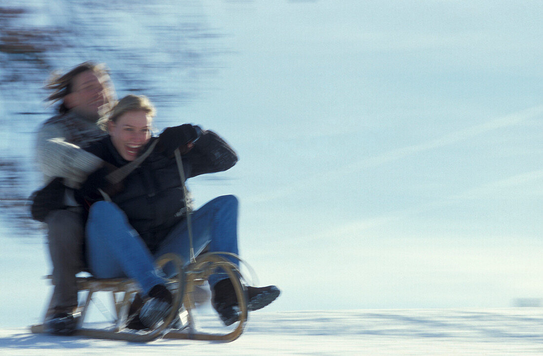 Couple sledding downhill