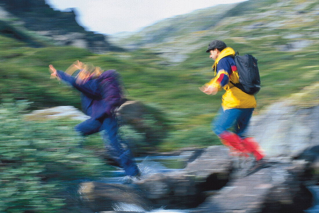 Wanderer springen über Felsen, Dumdalen im Jotunheimen Nationalpark, Norwegen