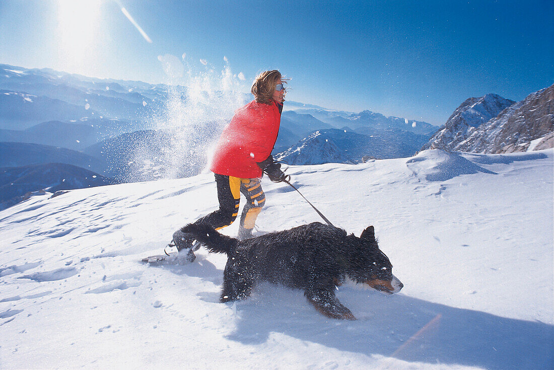 Eine Frau wandert mit Hund durch den Schnee