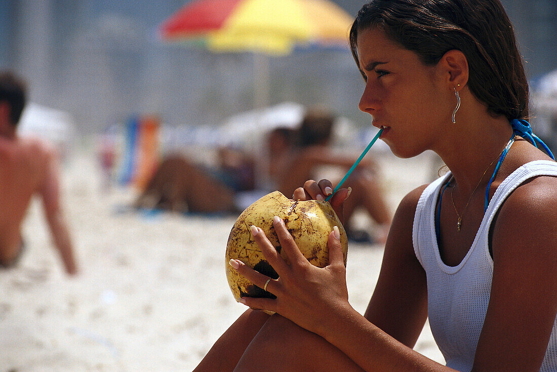 Girl drinking coconut milk on Ipanema Beach, Rio de Janeiro, Brazil, South America, America