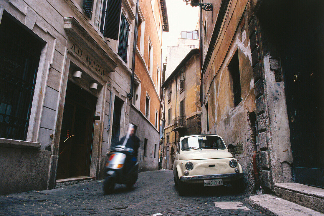 Mann fährt auf einem Motorroller durch eine Gasse der Altstadt, Rom, Italien