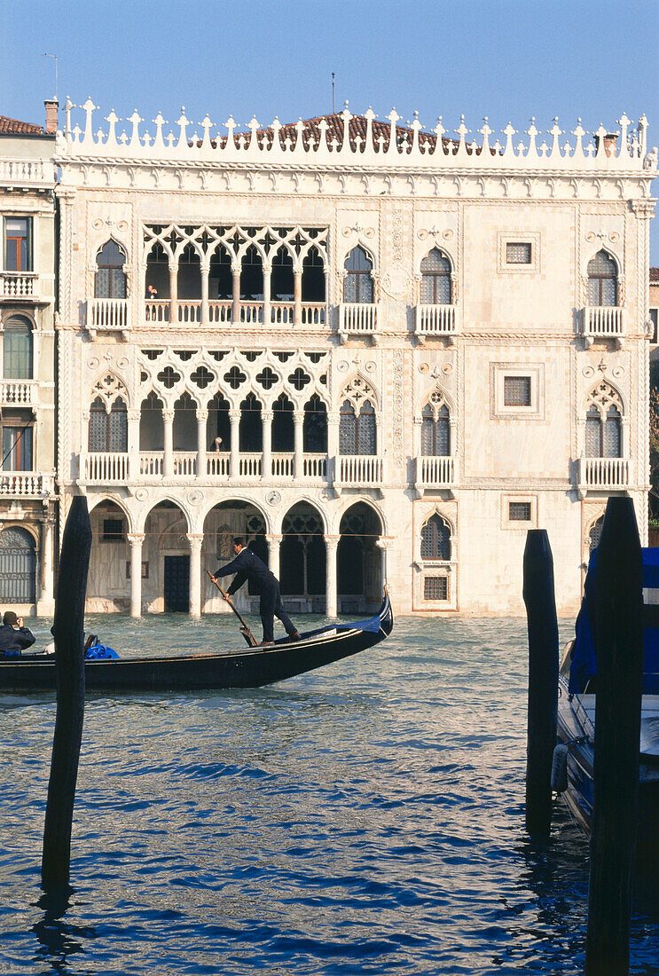 Eine Gondel fährt vor einem Palast über den Canale Grande, Venedig, Italien