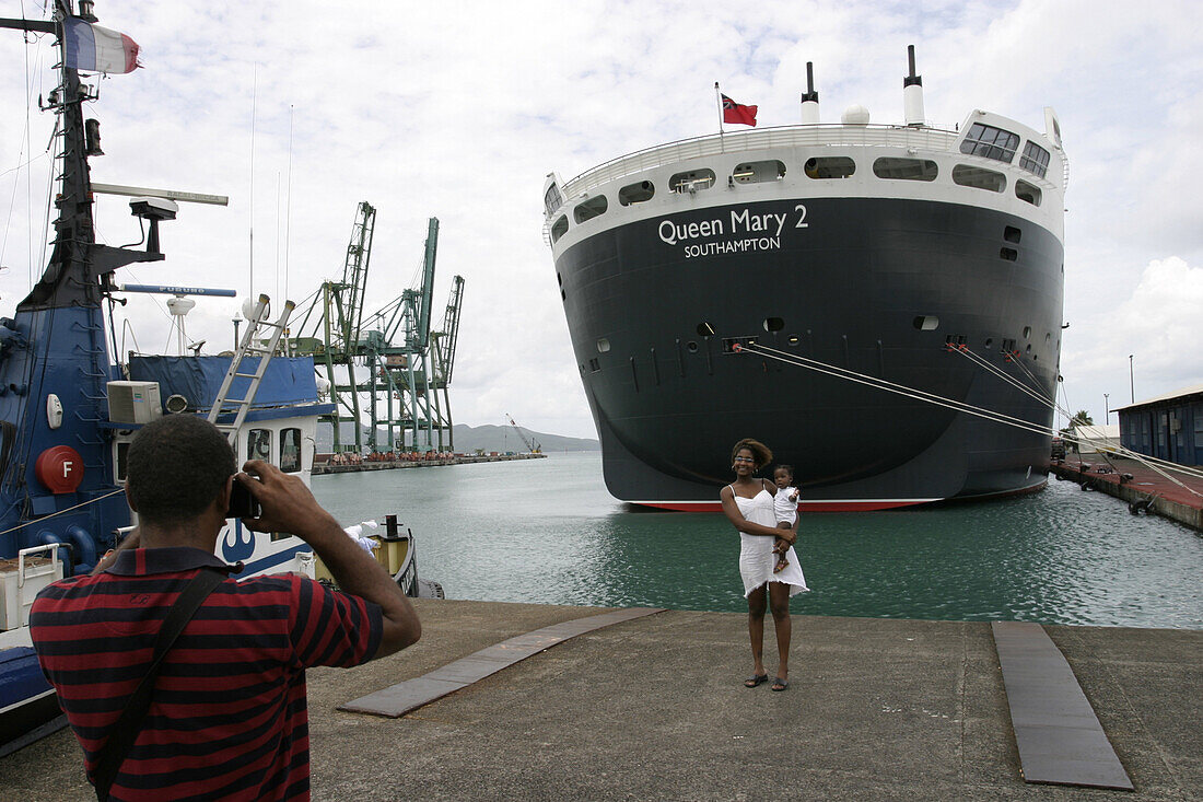 Queen Mary 2, Quay of Fort-de-France, Martinique, Queen Mary 2, QM2 Anleger fuer Kreuzfahrtschiffe im Hafen von Fort de France, Martinique. Eine einheimische Familie macht ein Erinnerungsfoto.