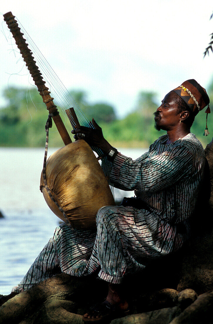 Man playing a harp by the Gambia river, Gambia, Africa