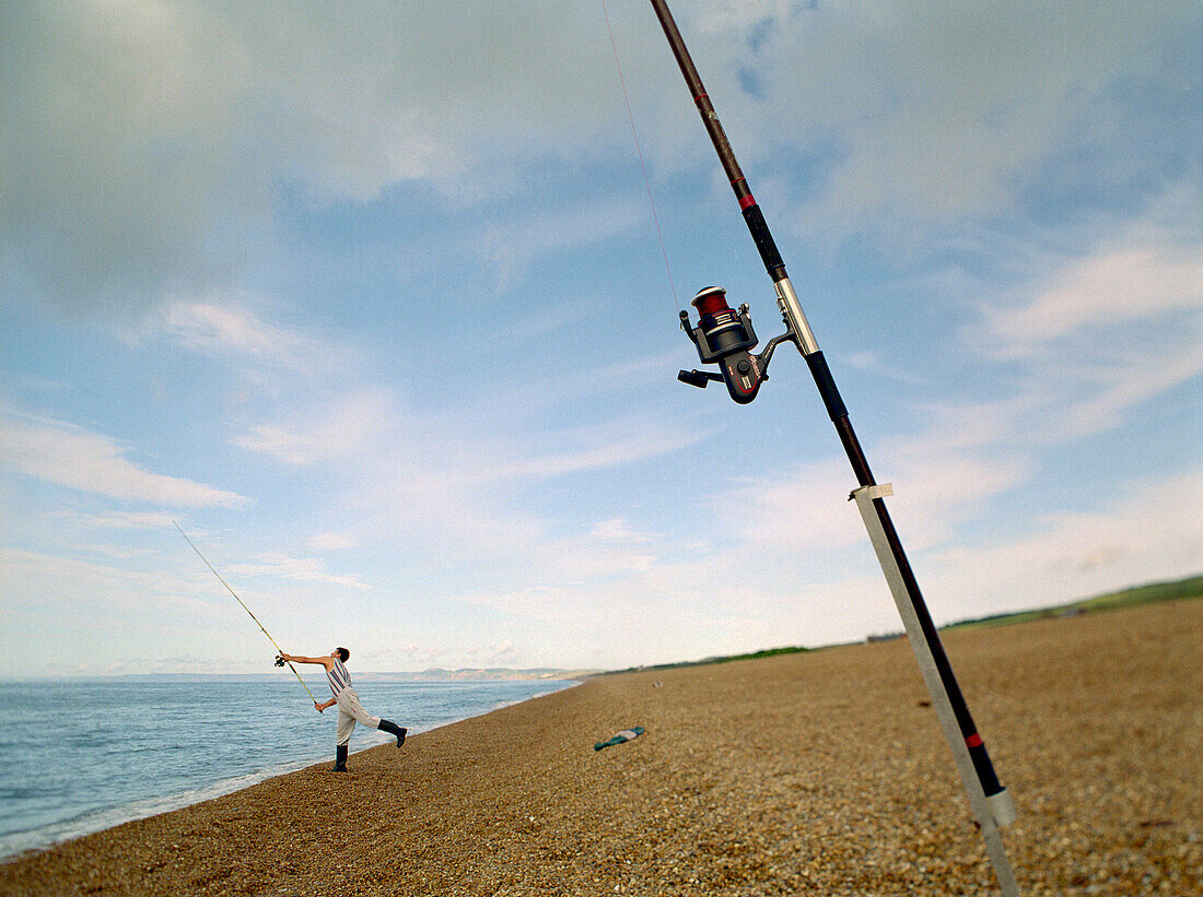 Young man fishing on the beach, Chesil Bank, Dorset, South England, England, Great Britain
