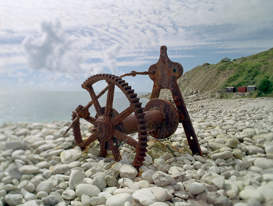 Rusty object on a pebbled beach, Seaside near Church Ope Cove, South England, England, Great Britain