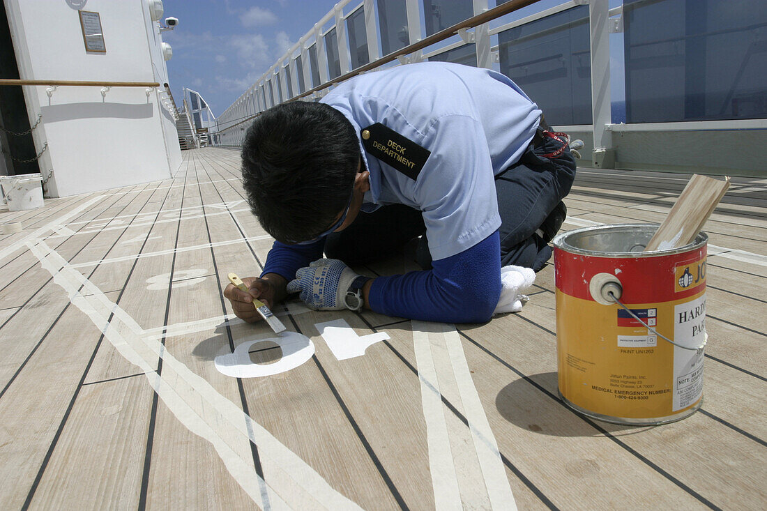 Queen Mary2-Painting figures for shuffleboard game, Queen Mary 2, QM2 Besatzungsangehörige malen die Zahlen des Shuffleboard Spieles mit weisser Farbe nach. Deck 12.