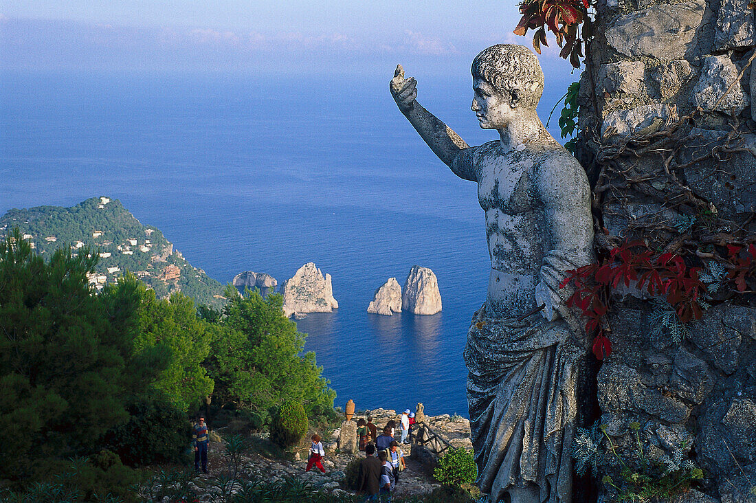 Weathered stone figure and group of tourists at the coast, Monte Solaro, Faraglioni, Capri, Italy, Europe