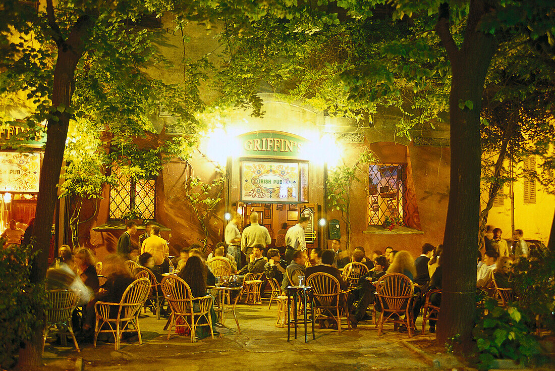 Menschen sitzen abends vor Griffin´s Pub unter Bäumen, Largo Square, Modena, Emilia Romagna, Italien, Europa