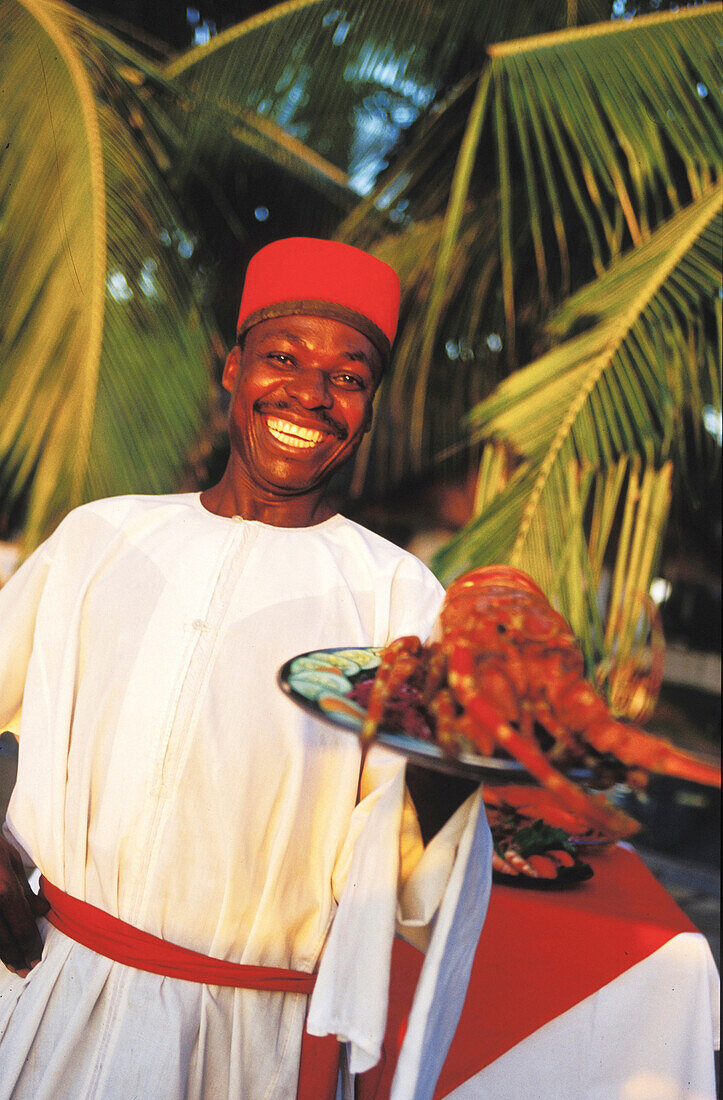 Waiter with seafoodplatter, people smiling