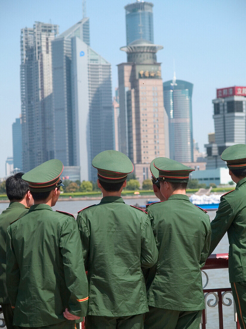 Men in uniforms in front of skyline, Shanghai, China