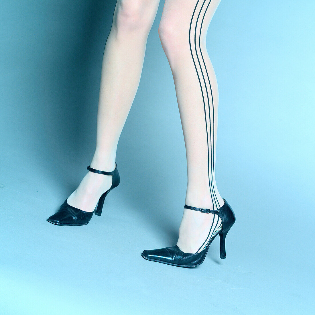 Young woman in stockings with stripes wearing high heel pump