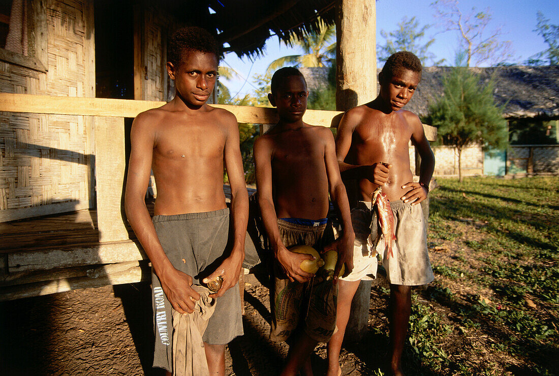Three boys standing in front of a hut, Sanesup, Ambrym, Vanuatu, South Seas