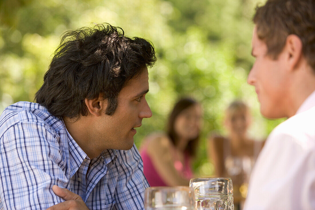 Two young men talking in beer garden, Munich, Bavaria