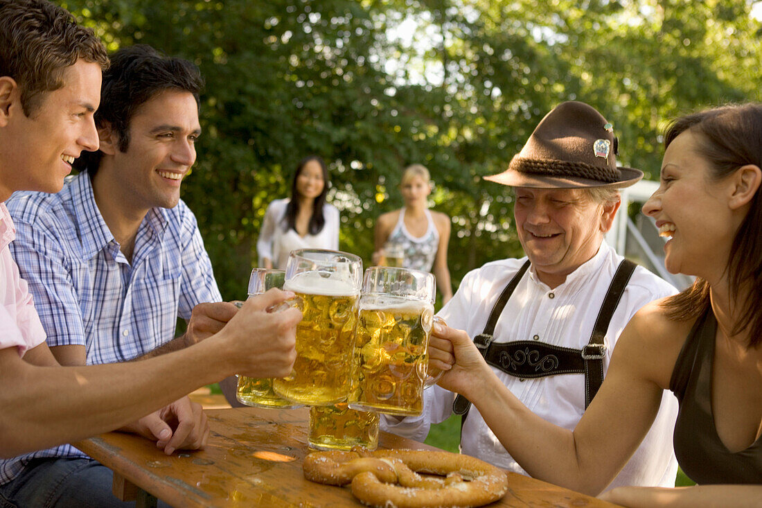 Four people toasting each other in beer garden, Munich, Bavaria