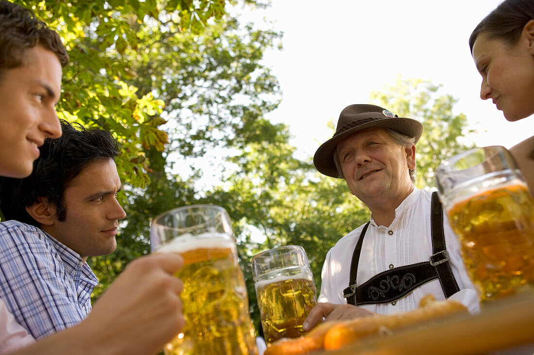 Young people and older man sitting in beer garden, Munich, Bavaria