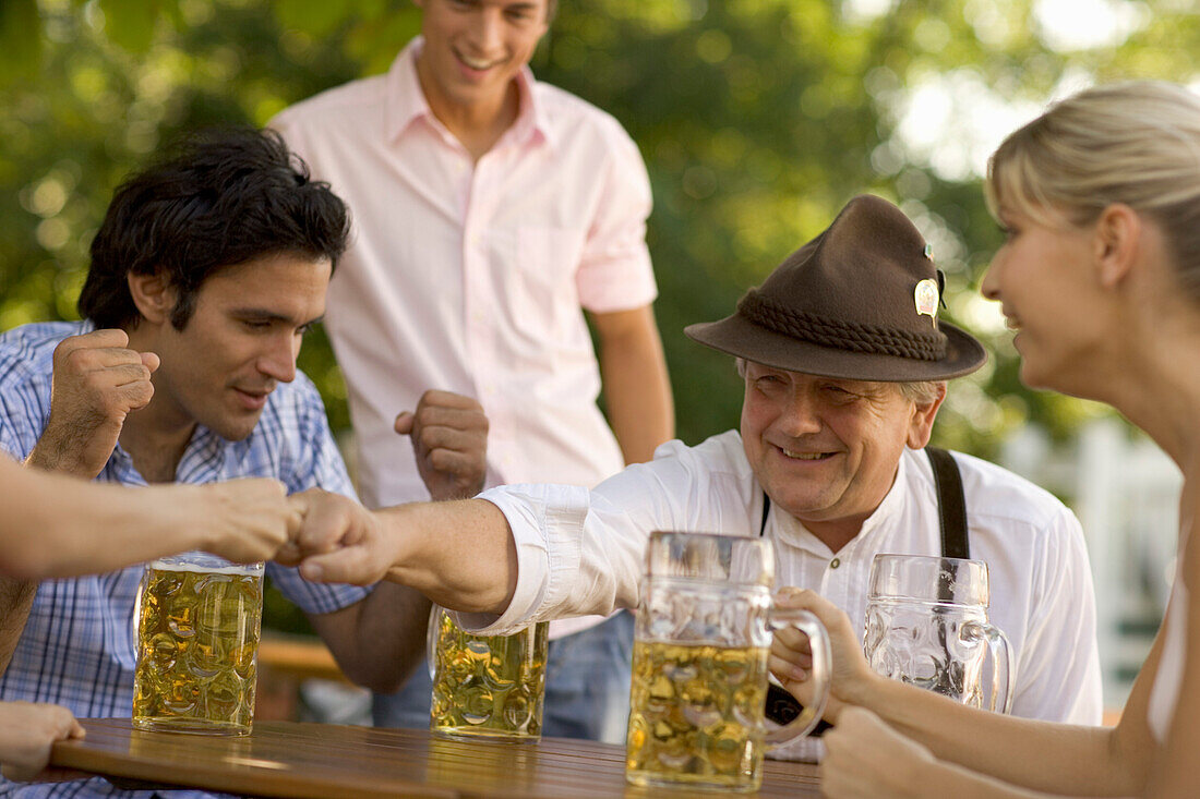 Cheerful people playing game in beer garden, Fingerhakeln, Munich, Bavaria