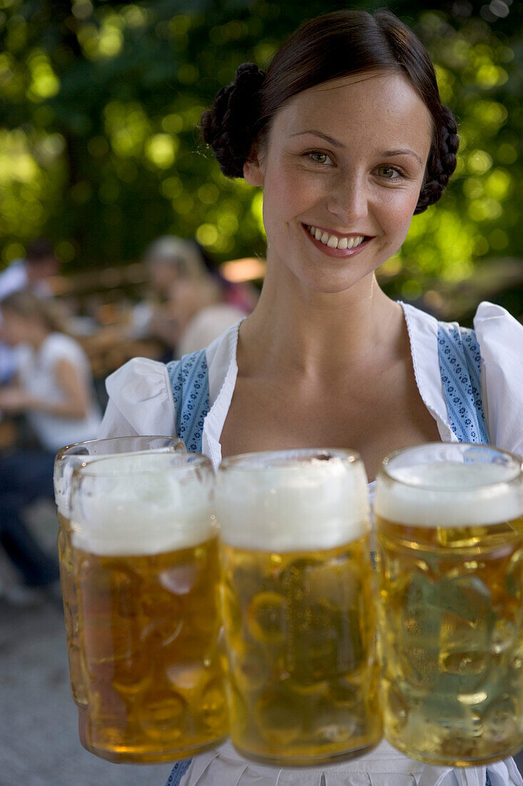 Young waitress with beer steins in beer garden, Munich, Bavaria