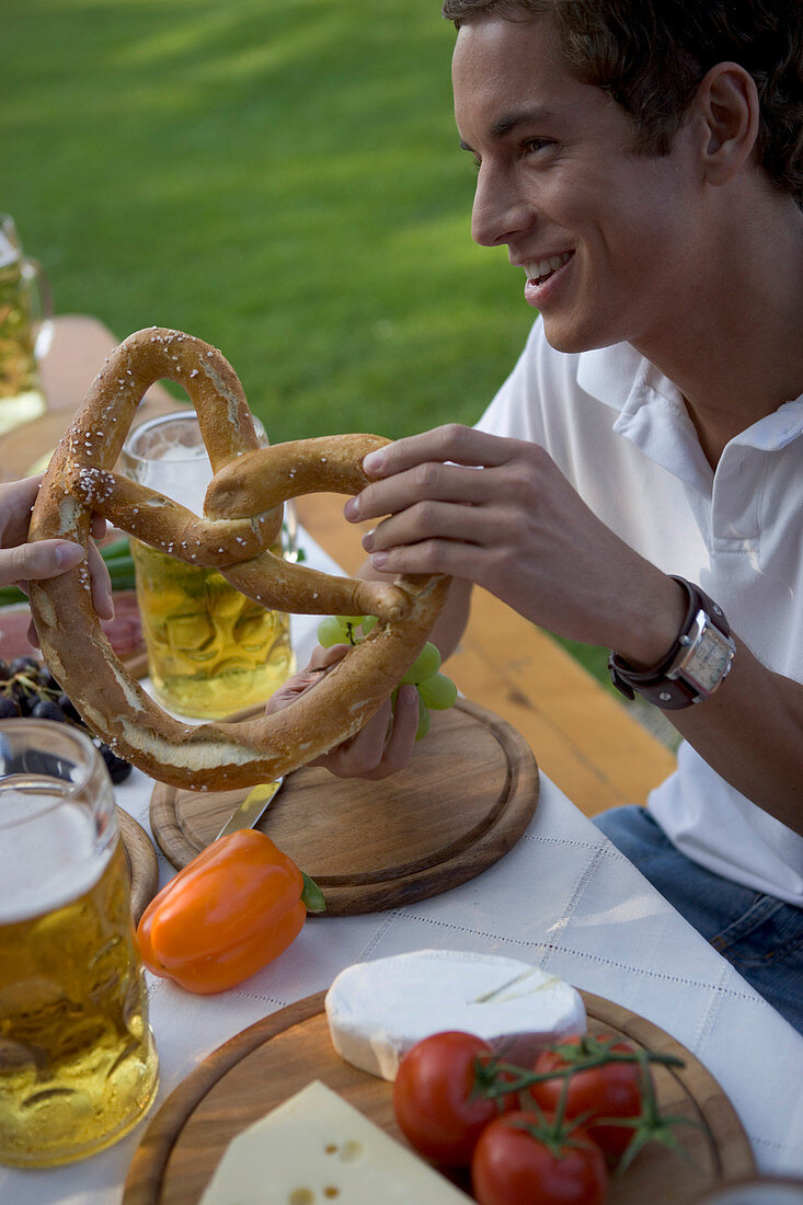 Young man with snack and beer stein in beergarden near Lake Starnberg, Bavaria, Germany