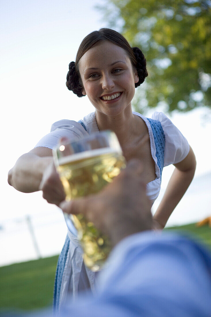 Waitress serving beer stein to guest in beer garden, Munich, Bavaria