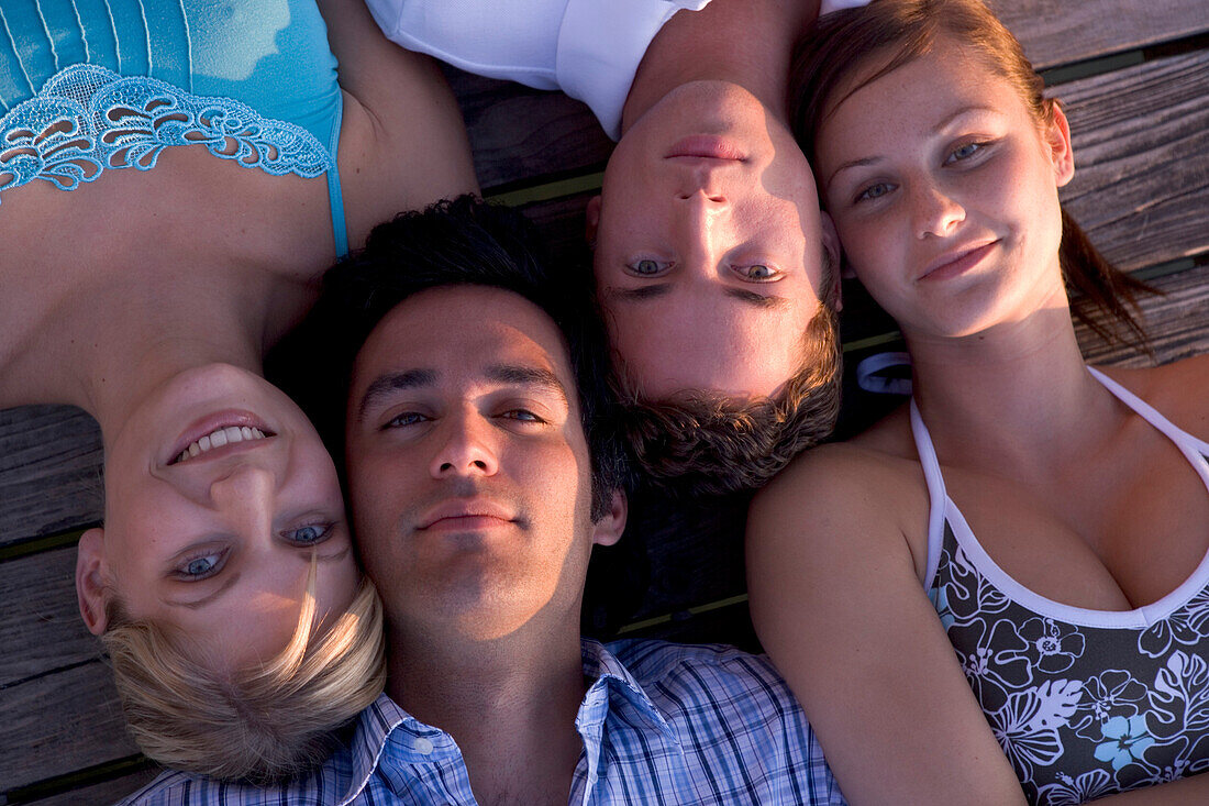 Four young people lying at boardwalk and looking into camera, Munich, Bavaria