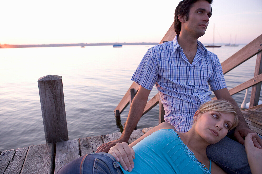 Young couple lying on boardwalk at sunset, Munich, Bavaria