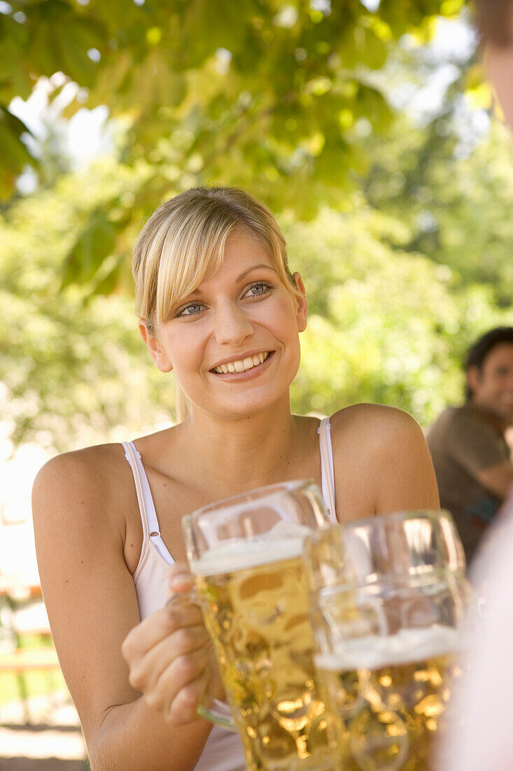 Young woman toasting with beer stein, Munich, Bavaria