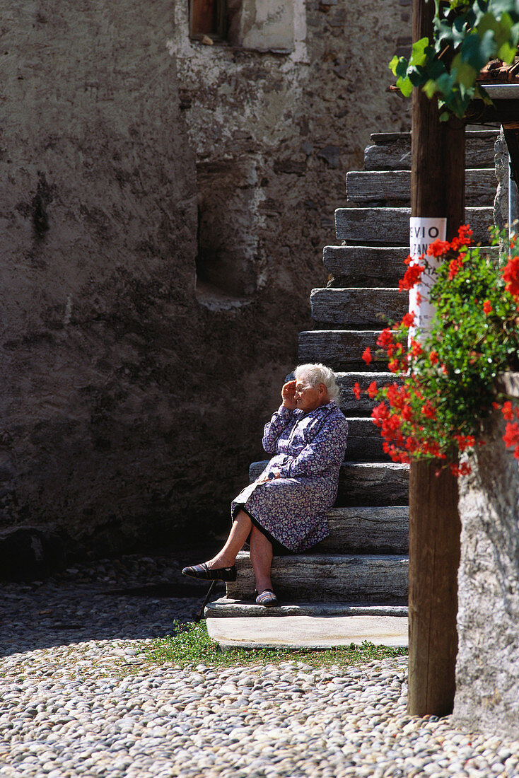 Seniorin sitzt auf der Treppe, Tessin, Schweiz