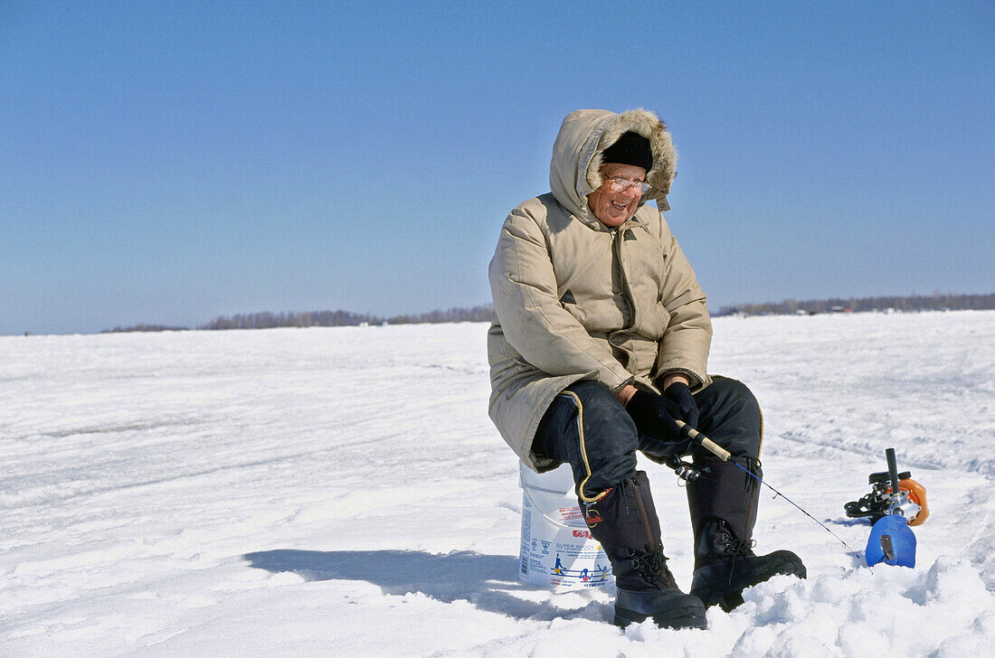 Ice Fishing, a man sitting on frozen St. Lawrence River, Quebec, Canada