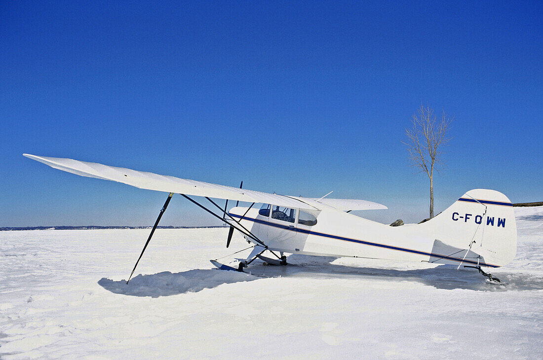 Ein Flugzeug steht auf dem gefrorenen Fluss in der Sonne, St. Lawrence River, Quebec, Kanada