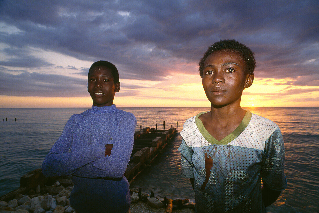 Zwei Jungen stehen in der Morgendämmerung am Strand, Jamaika