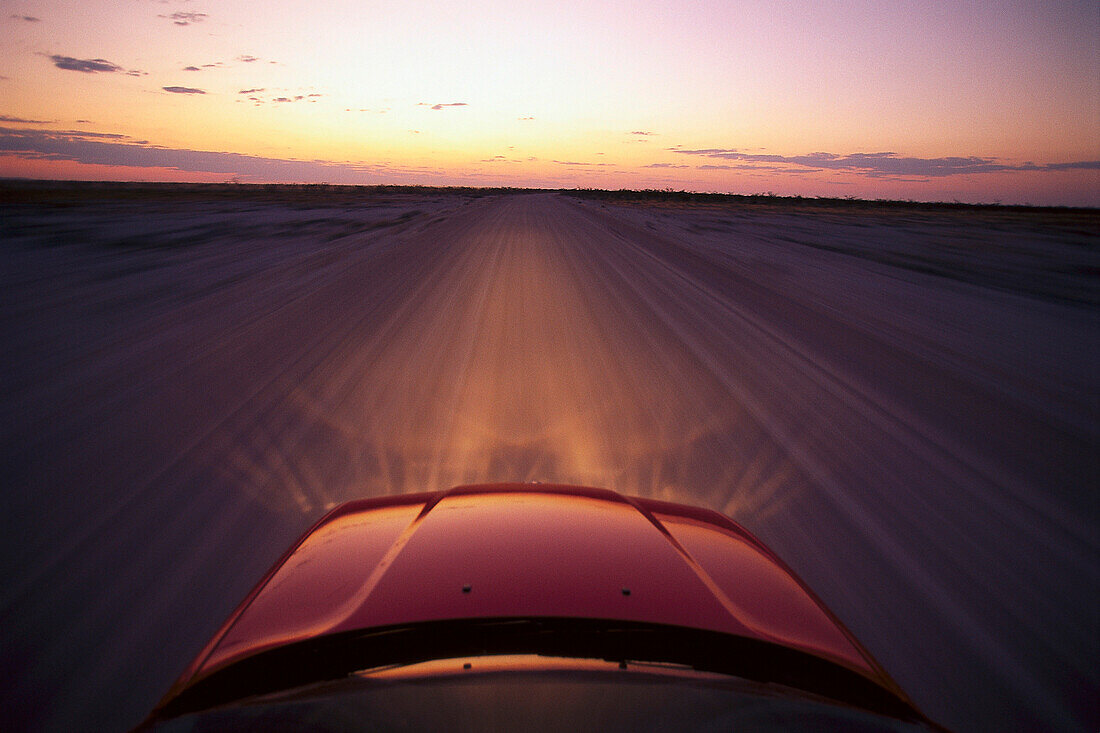 Blick auf die Kühlerhaube eines BMW auf einer Schotterstrasse bei Sonnenuntergang, Namibia, Afrika