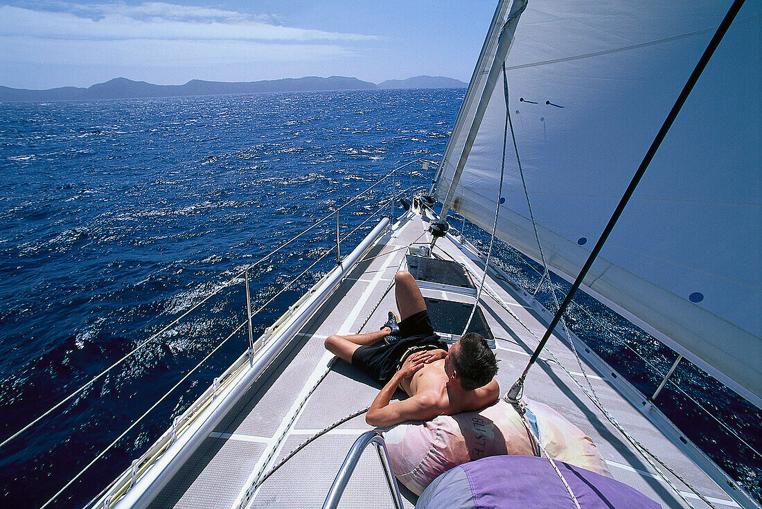 A man sunbathing on the bow of a sailing boat, Bequia, St. Vincent, Grenadines, Caribbean, America
