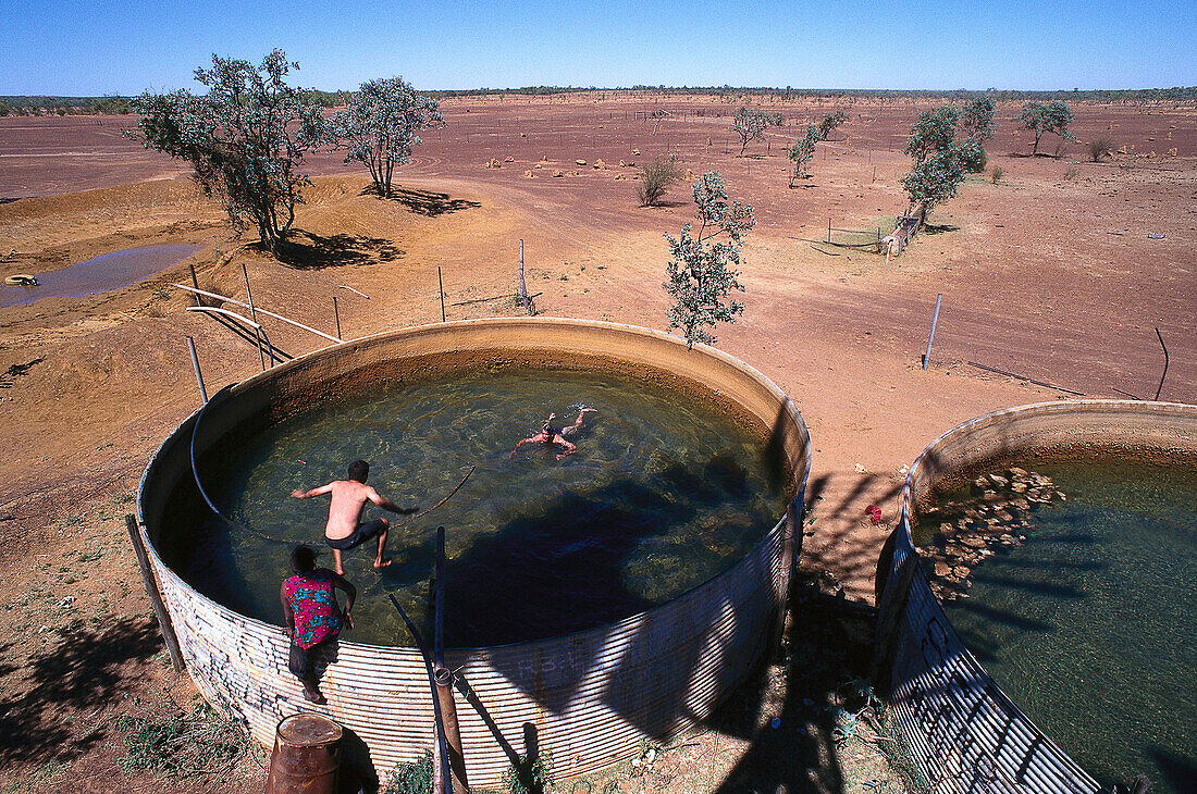 Männer baden in Wasserreservoir für Rinder, Windmill, Queensland, Australien