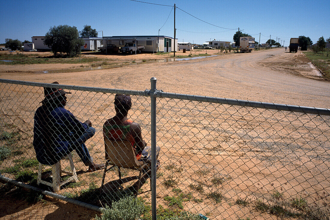 Two people sitting on the side of the road, Simpson Desert, Queensland, Australia