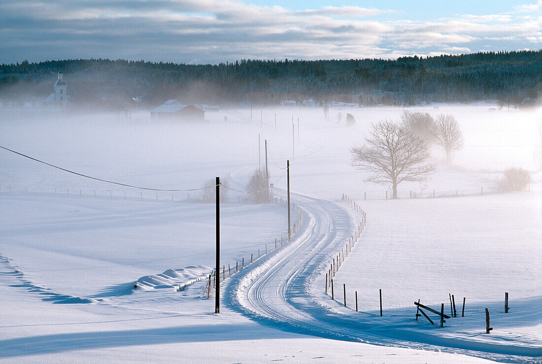 Early morning mist over snow covered country road, Vastergotland, Sweden