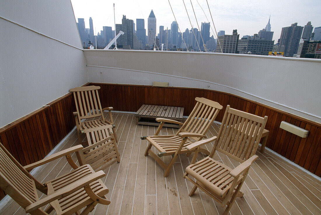 Stühle auf dem Deck des Kreuzfahrtschiffs Queen Elizabeth 2 und die Skyline von Manhattan
